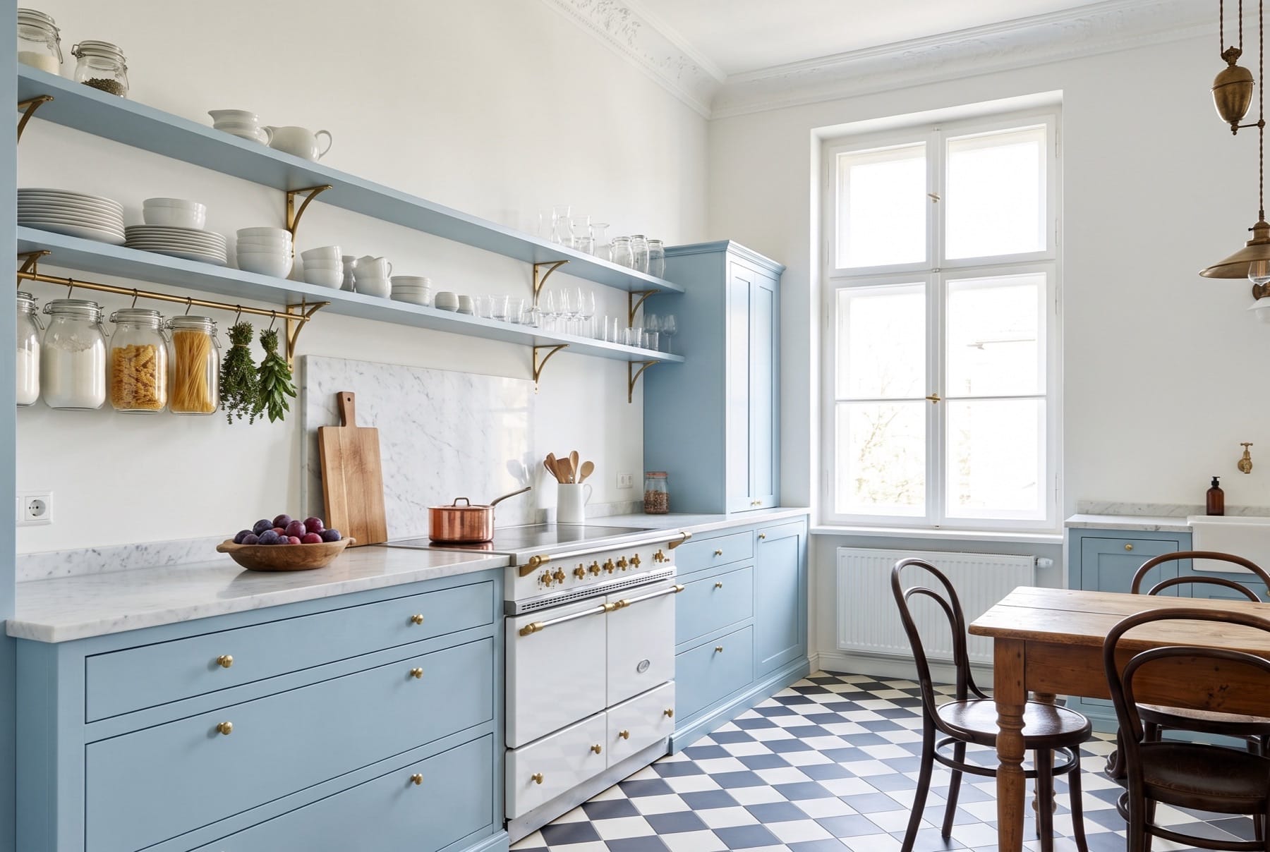 Altbauküche mit hellblauen Fronten, Marmorplatte und Schachbrettboden; Thonet-Stühle am Fenster, offene Regale mit Geschirr.